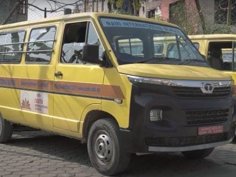 A yellow NAMI International School minibus parked in the school yard alongside the rest of the fleet.